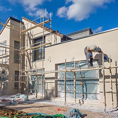 Man on scaffold painting outside of house