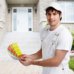 Man holding up color swatches outside of house