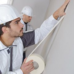 Team members placing tape before painting