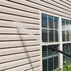 Person powerwashing siding before exterior painting