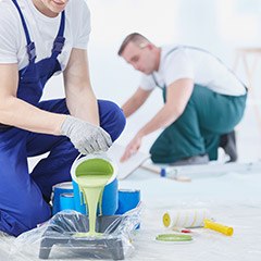 Two team members painting an interior wall